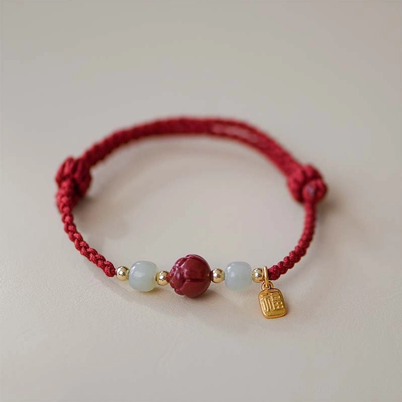 Cinnabar bracelet with gold fu charm pendant and white jade beads on light background