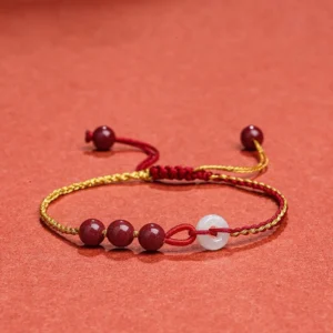 Cinnabar jade peace buckle blessing bracelet front view with red-gold woven rope and white jade peace buckle