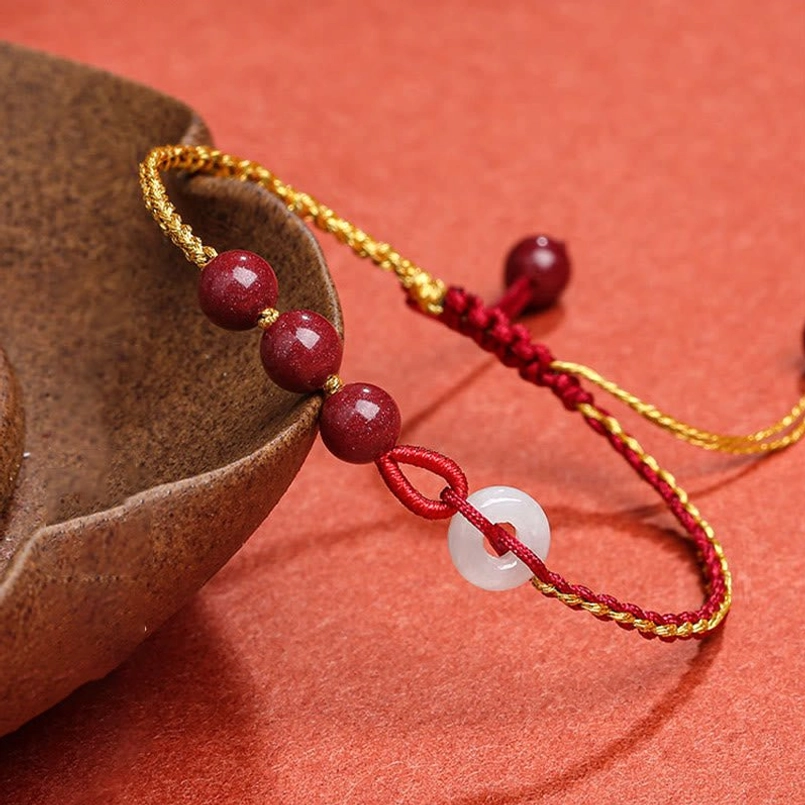 Cinnabar jade peace buckle bracelet side view showing braided red-gold cord and cinnabar beads