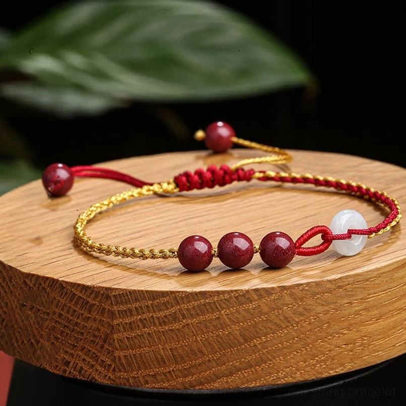 Cinnabar jade peace buckle bracelet on wooden display base with natural styling