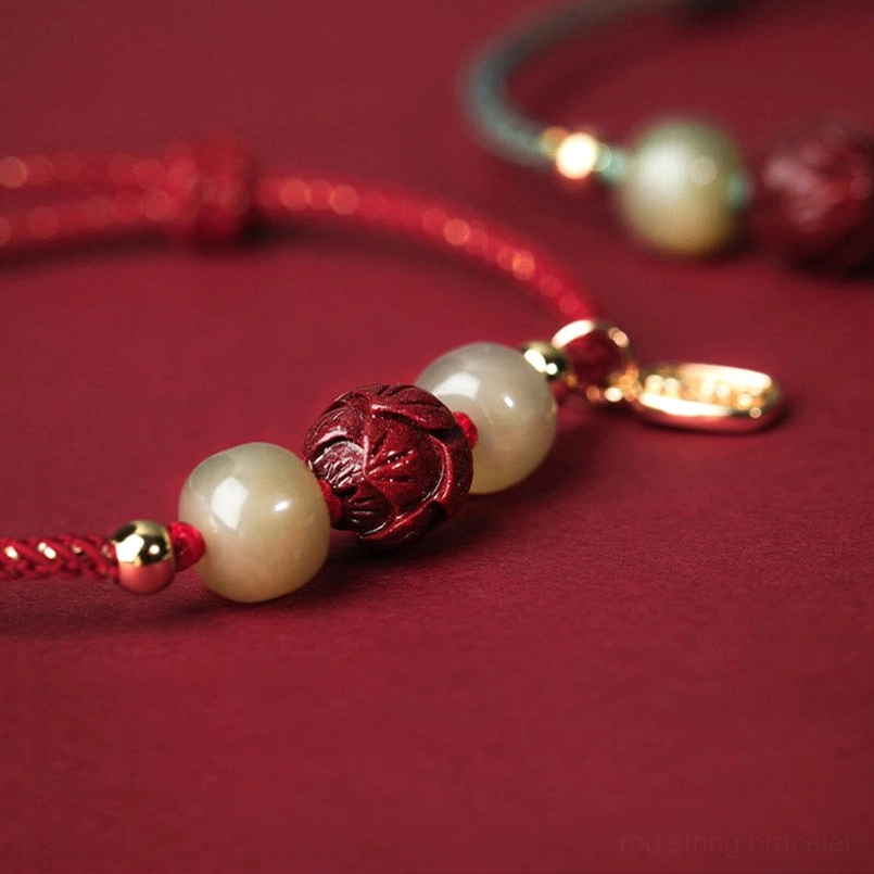 Close-up detail of carved cinnabar lotus bead and jade beads with gold metal findings
