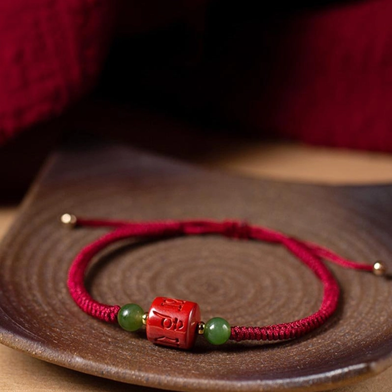 Detailed close-up of engraved cinnabar om mani padme hum bead with green jade beads