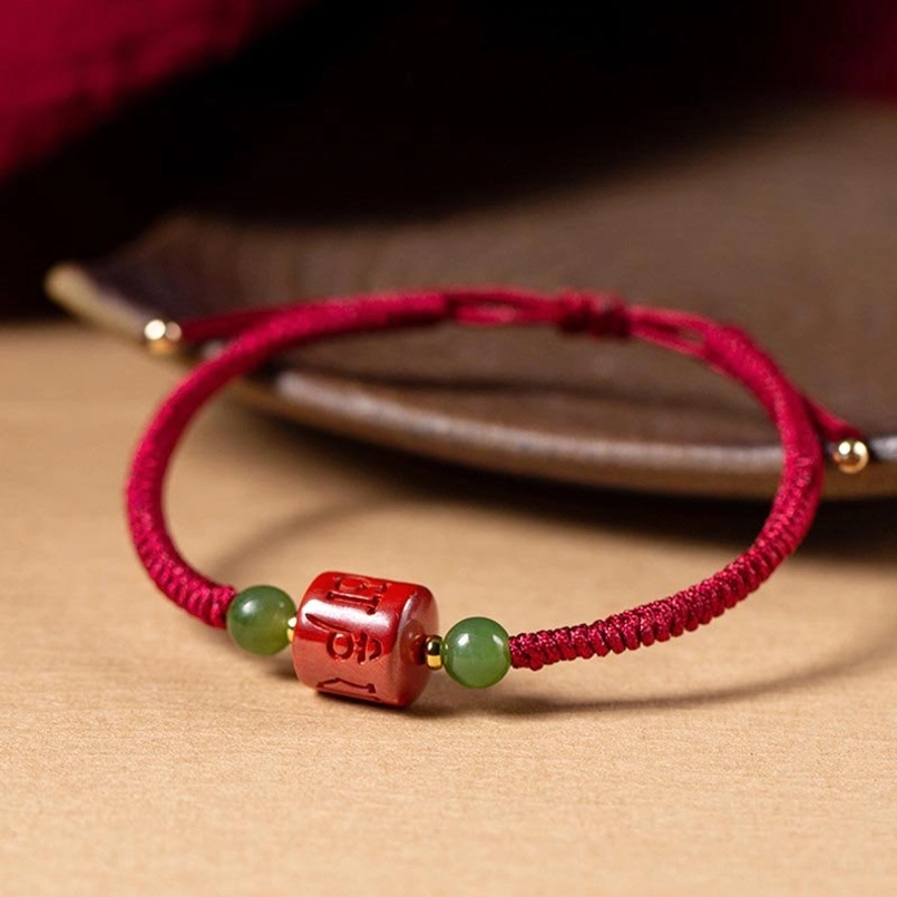 Close-up detailed view of cinnabar om mani padme hum engraved bead with jade accents