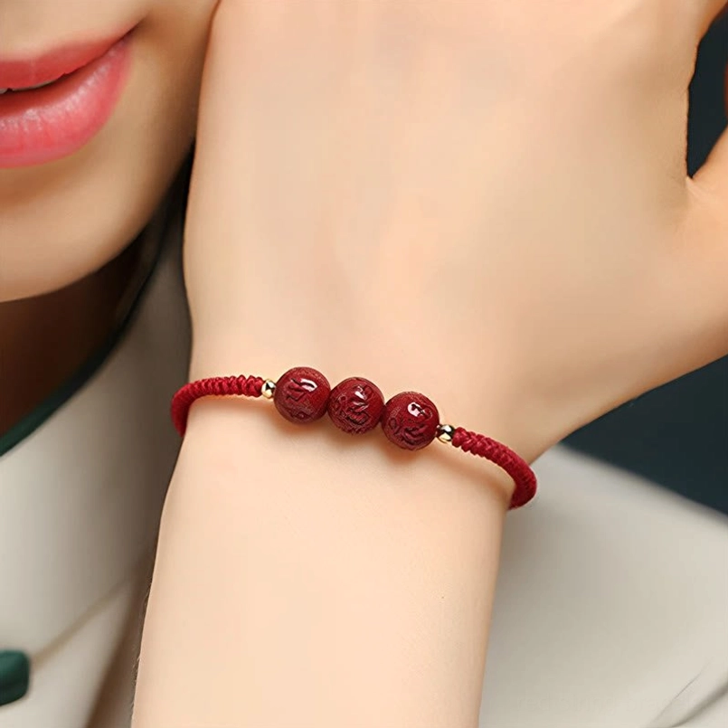 Cinnabar engraved beads with metal spacers and red braided cord close-up detail