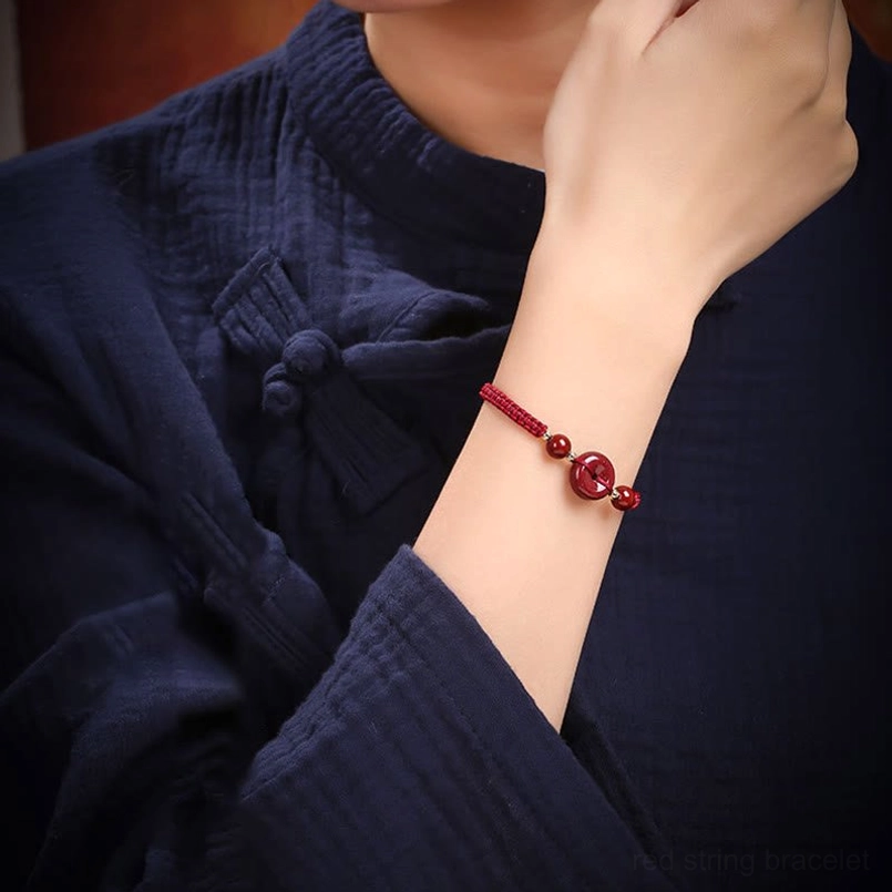 Cinnabar red string bracelet worn on wrist with traditional Chinese clothing