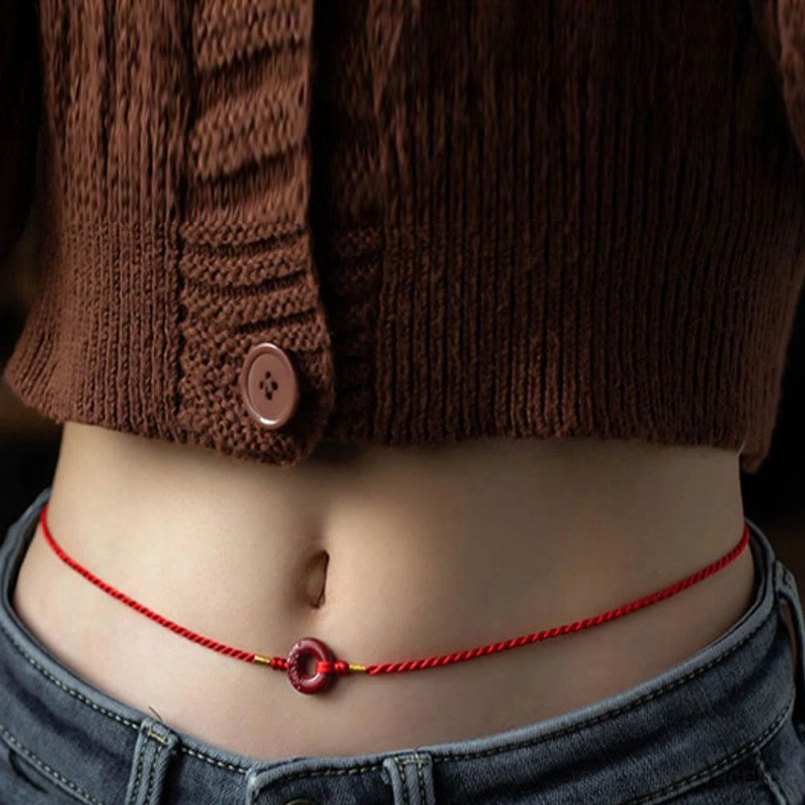 Close-up of cinnabar peace buckle belly chain pendant resting on bare waist