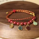 Cinnabar peace and joy red string blessing bracelet on dark wooden round tray