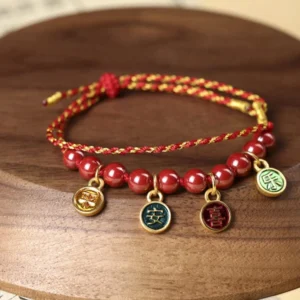 Cinnabar peace and joy red string blessing bracelet on dark wooden round tray