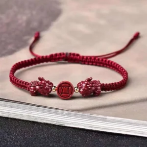 Cinnabar Pixiu copper coin red string bracelet with dual charms on vintage book