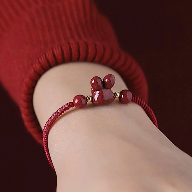 Back view of cinnabar rabbit bracelet worn on wrist, showing adjustable pull cord tail and proper fit on dark background