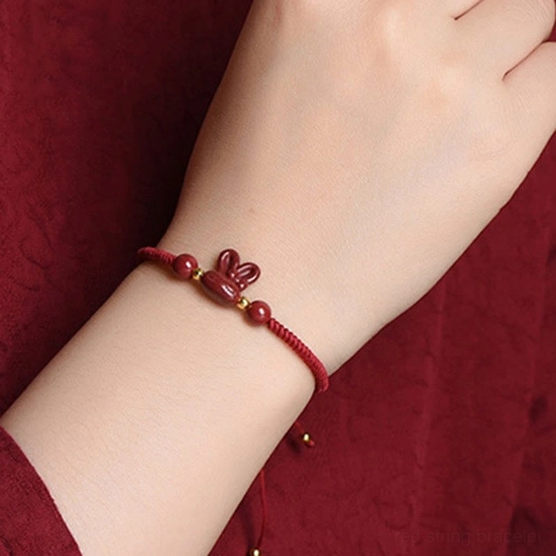 Front view of cinnabar rabbit red string bracelet worn on bare wrist, close-up of rabbit charm and round beads detail
