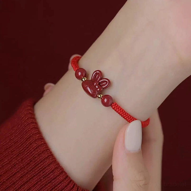 Cinnabar rabbit zodiac red string bracelet full product view on bright red background, adjustable cord with gold end caps