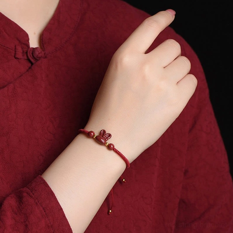 Woman wearing red string rabbit bracelet on left wrist with traditional red Chinese clothing, cultural styling photo