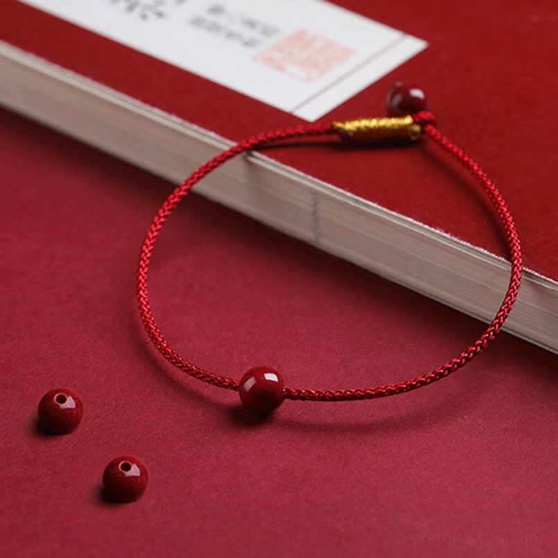 Cinnabar protection bracelet displayed on red book with loose beads