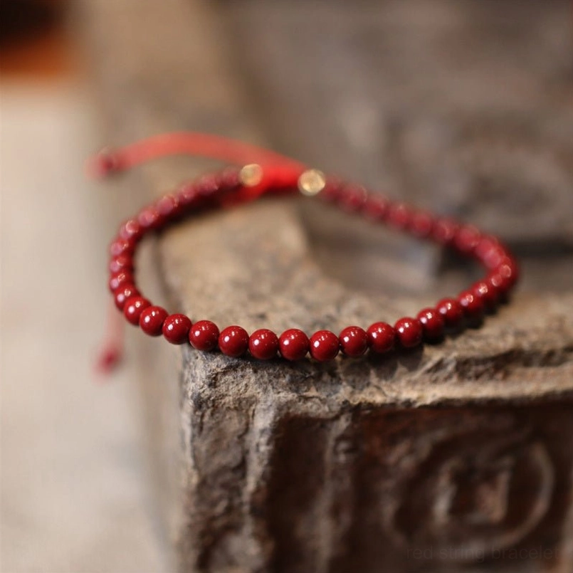 Natural cinnabar red string bracelet with dark red round beads and adjustable cord on stone surface