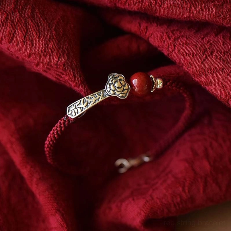 Cinnabar red string bracelet with carved silver Ruyi ornament low angle photography