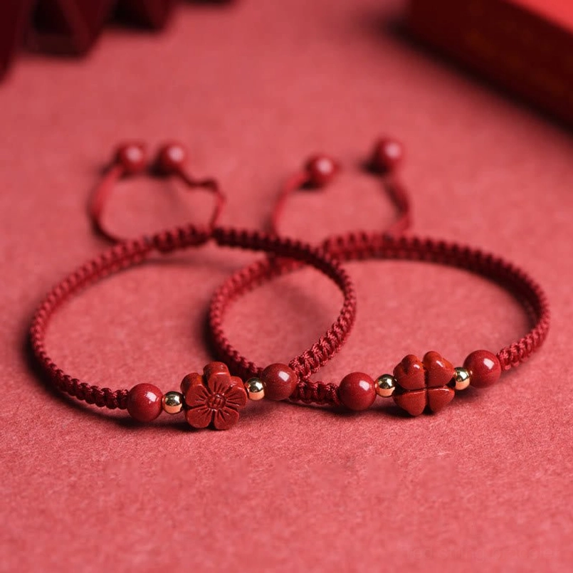 Multiple five-petal flower cinnabar red string bracelets with adjustable pull-tie knots flat lay
