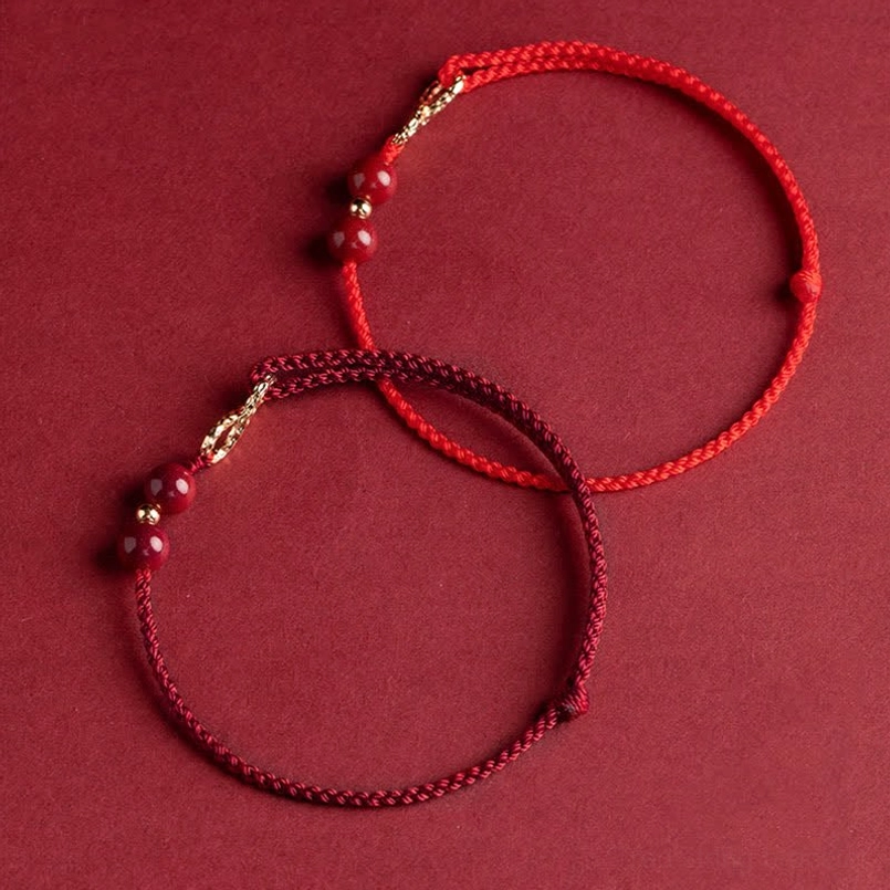 Premium cinnabar red string bracelet detail shot showing bead quality and gold infinity symbol