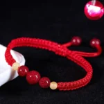 Red cinnabar string bracelet for kids with braided rope and adjustable tassel, flat lay overhead view