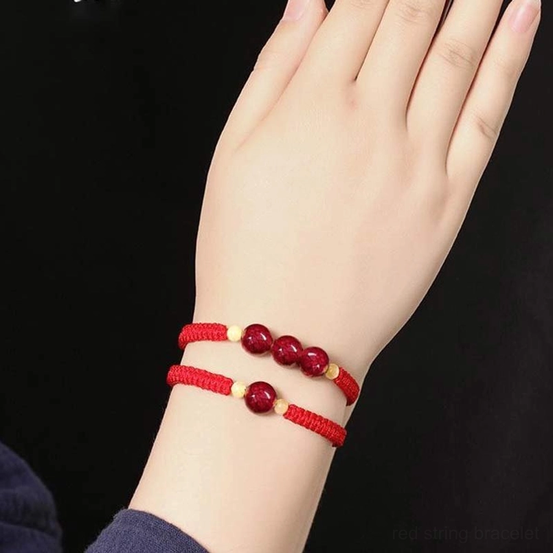 Stacked red cinnabar bracelets on child's wrist side view, slim braided design for comfortable fit