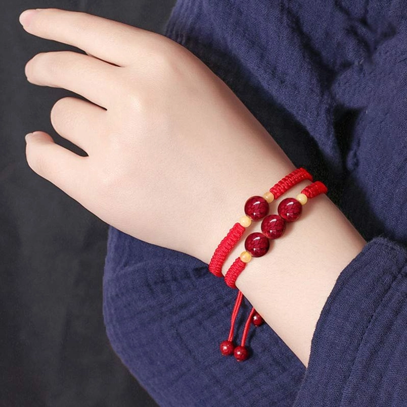 Slim red cinnabar string bracelet on side of wrist, minimalist design for kids, casual daily wear