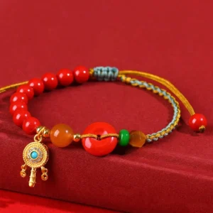 Cinnabar red string peace buckle blessing bracelet flat lay on red fabric background