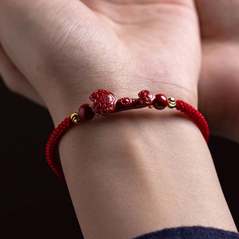 Cinnabar red string bracelet worn on wrist with Ruyi charm and gold accent beads