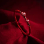 Handmade cinnabar red string bracelet with Ruyi charm and gold spacer beads, close-up side view