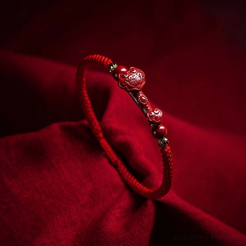 Handmade cinnabar red string bracelet with Ruyi charm and gold spacer beads, close-up side view