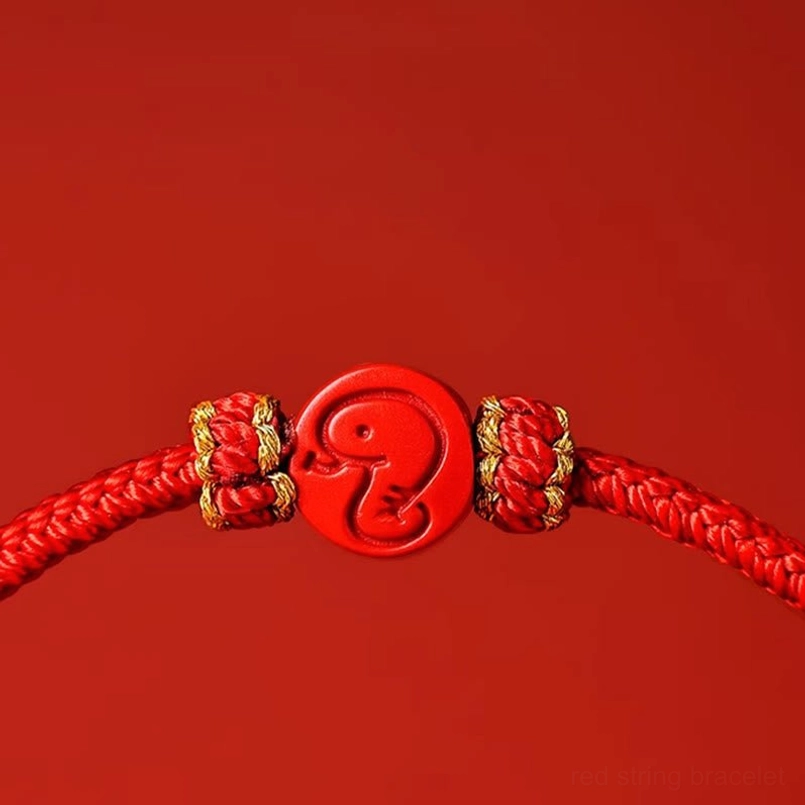 Close-up of snake zodiac cinnabar charm with detailed carving and gold woven knots