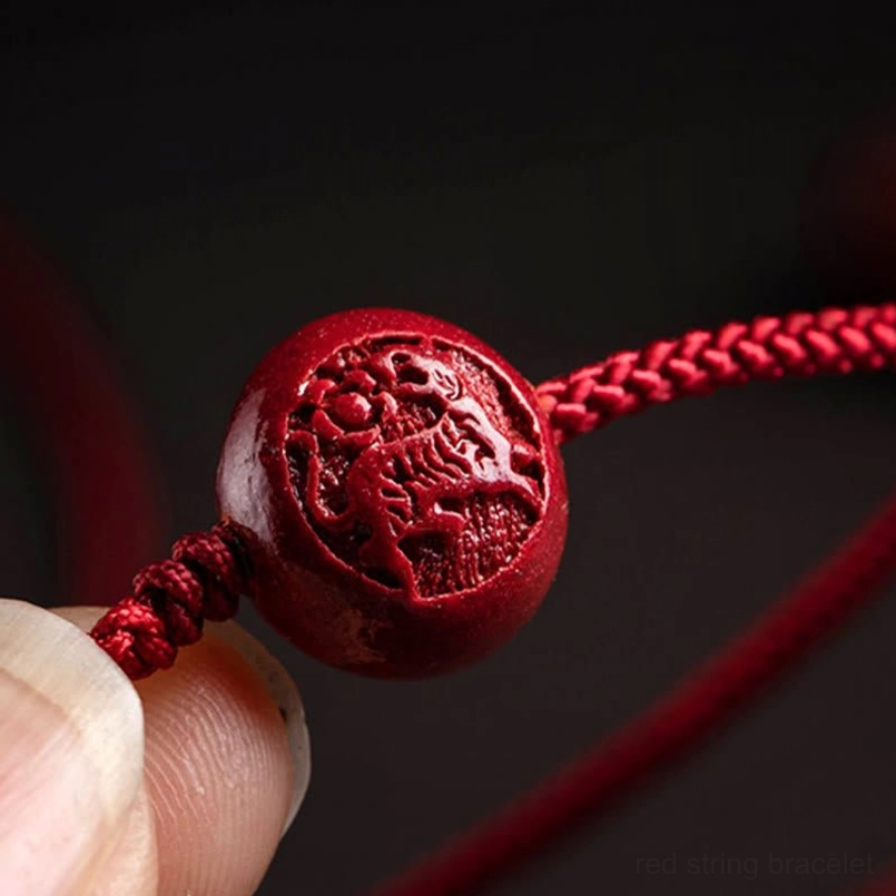 Extreme close-up of natural cinnabar zodiac pendant with detailed engraved animal pattern