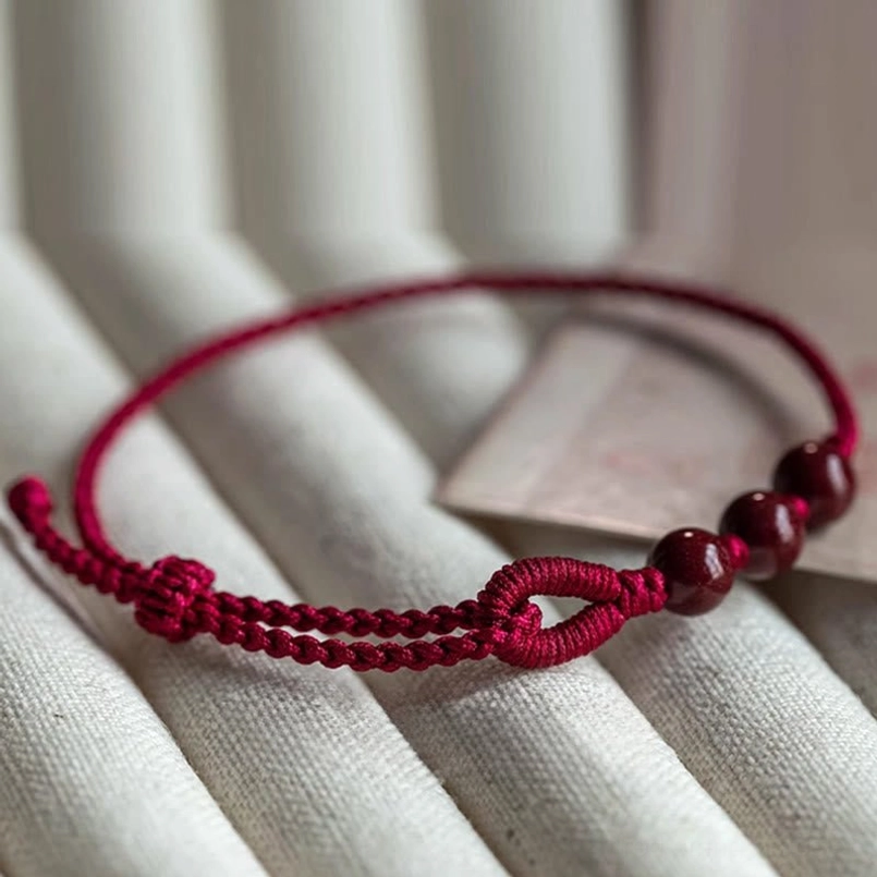 Close up view of cinnabar bead red string bracelet woven knot detail