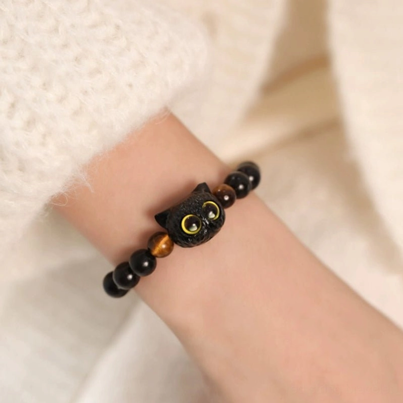 Close up shot of ebony cat head red string bracelet on slim wrist