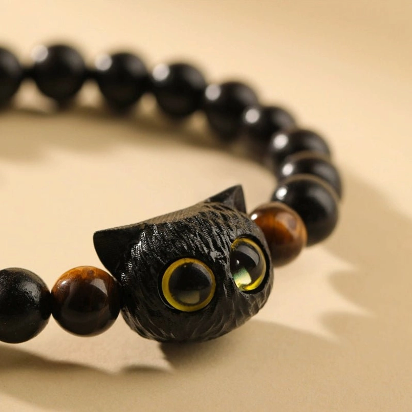 Close up of hand carved ebony cat head charm red string bracelet