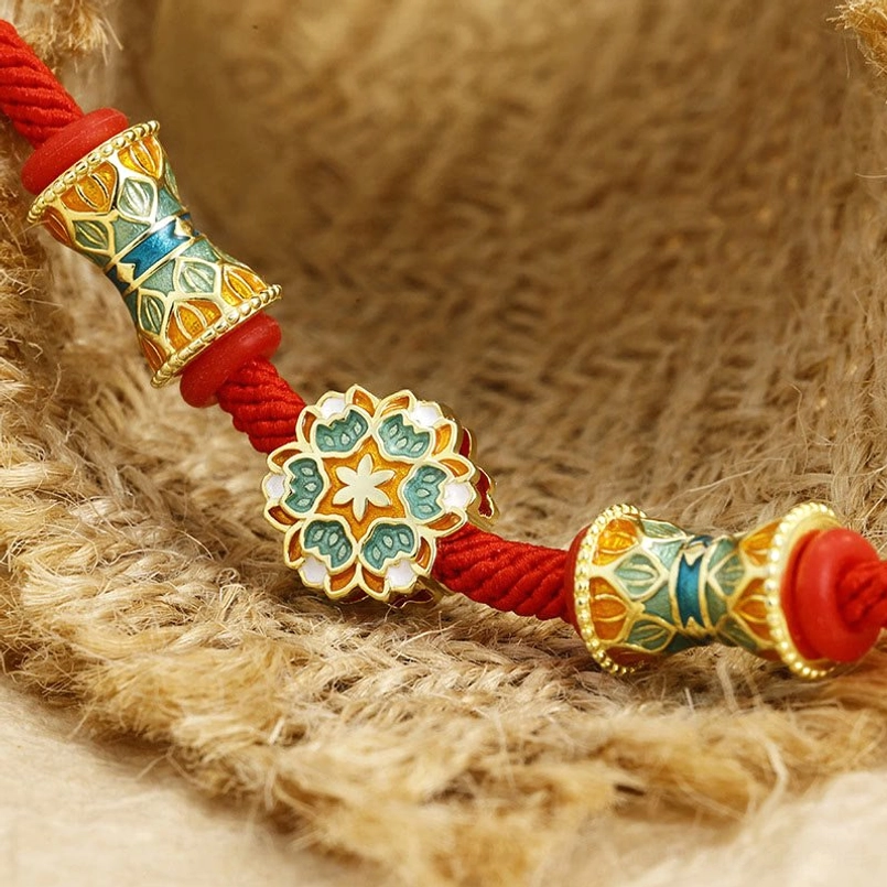 Close up view of 3D enamel lotus drum charms on Dunhuang red string bracelet