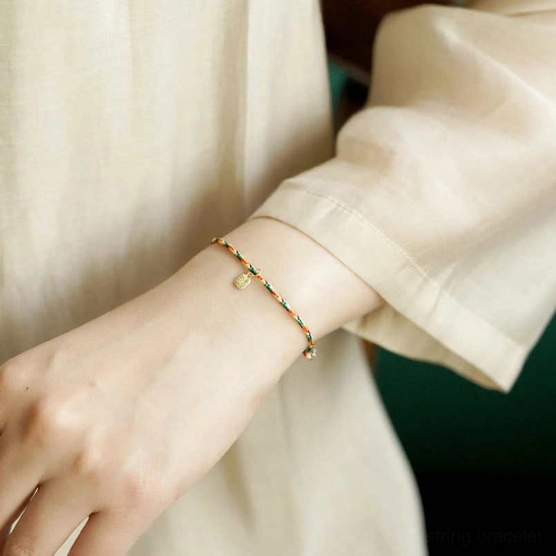 Close up of multicolor Fu character lucky bracelet worn on wrist with linen clothing