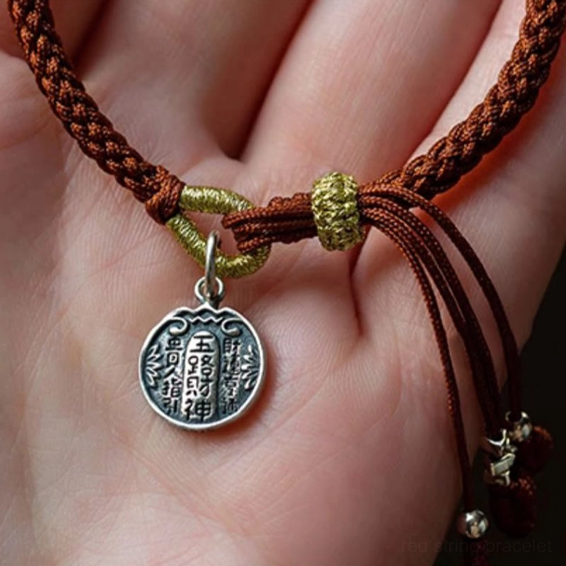 Close up of palm holding five directions wealth gods woven bracelet with silver charm