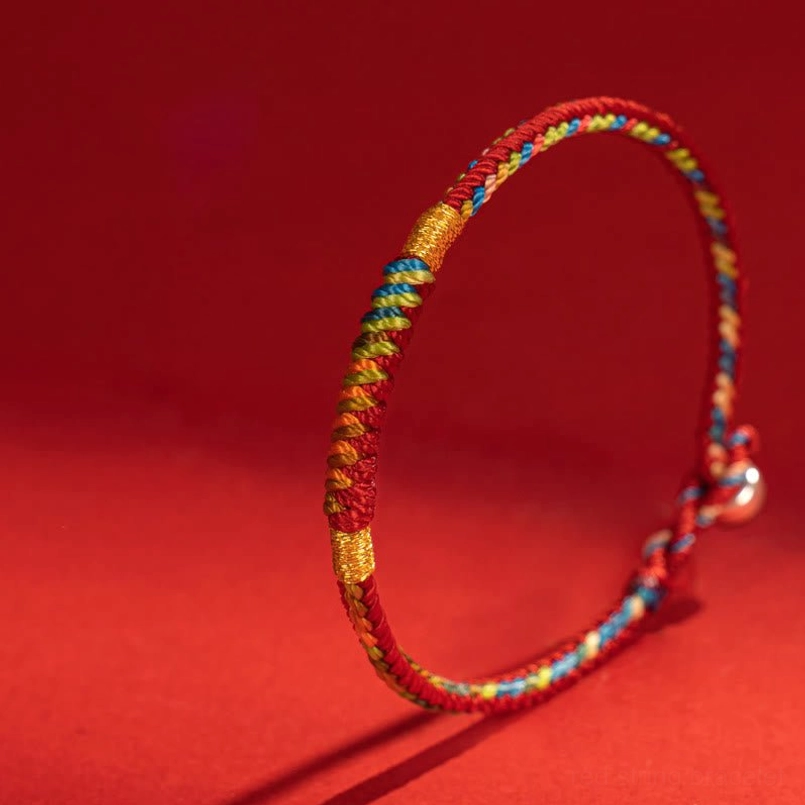 Colored woven red string bracelet with silver buckle on solid red background
