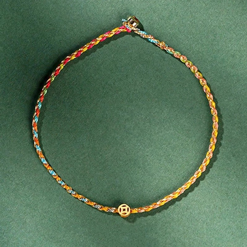 Full-length colorful braided lucky coin bracelet flat lay with rainbow woven cord and gold charm