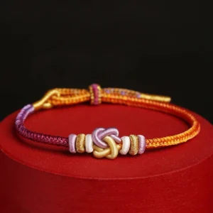 Colorful heart knot protection string bracelet with orange wine red purple and gold threads on display stand
