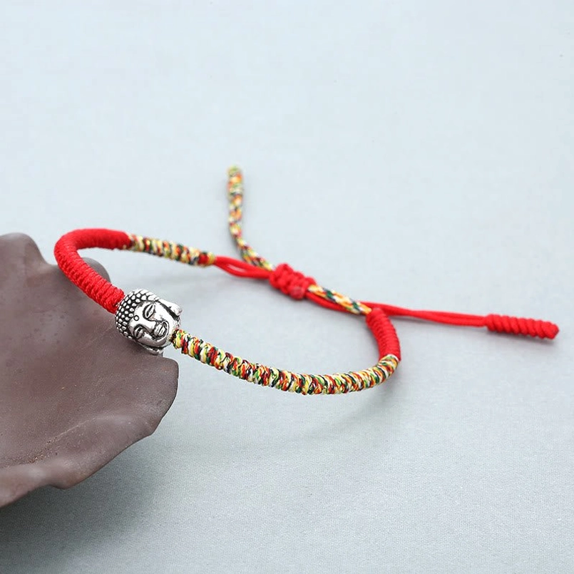 Colorful King Kong Knot Buddha luck string bracelet side view on brown ceramic prop
