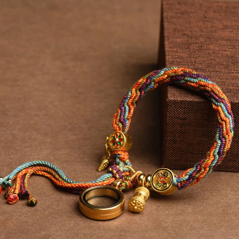 Tibetan red string bracelet with tassel and ring pendant low angle shot on wooden surface