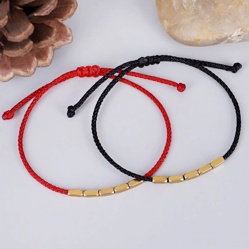 Red and black braided string bracelets with gold copper beads, lifestyle flat lay