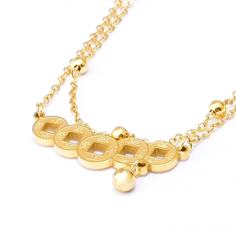 Flat lay close-up of engraved copper coin anklet with bell charm and multi-strand gold chain design