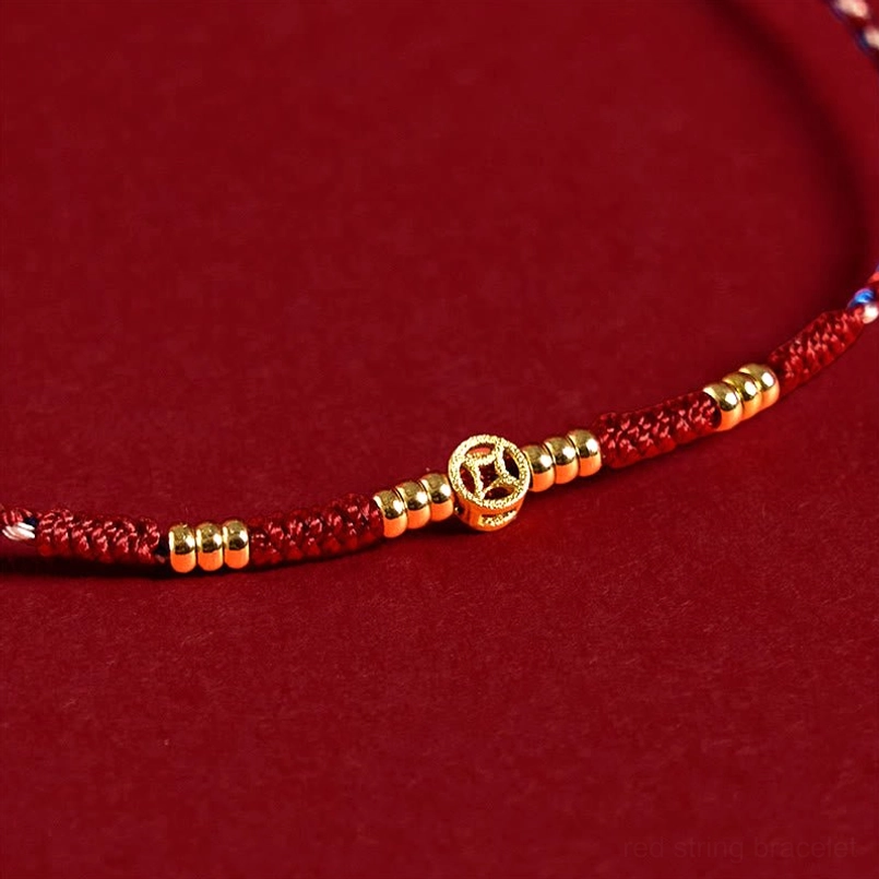 Close-up macro view of copper coin charm and gold spacer beads on handmade red string bracelet