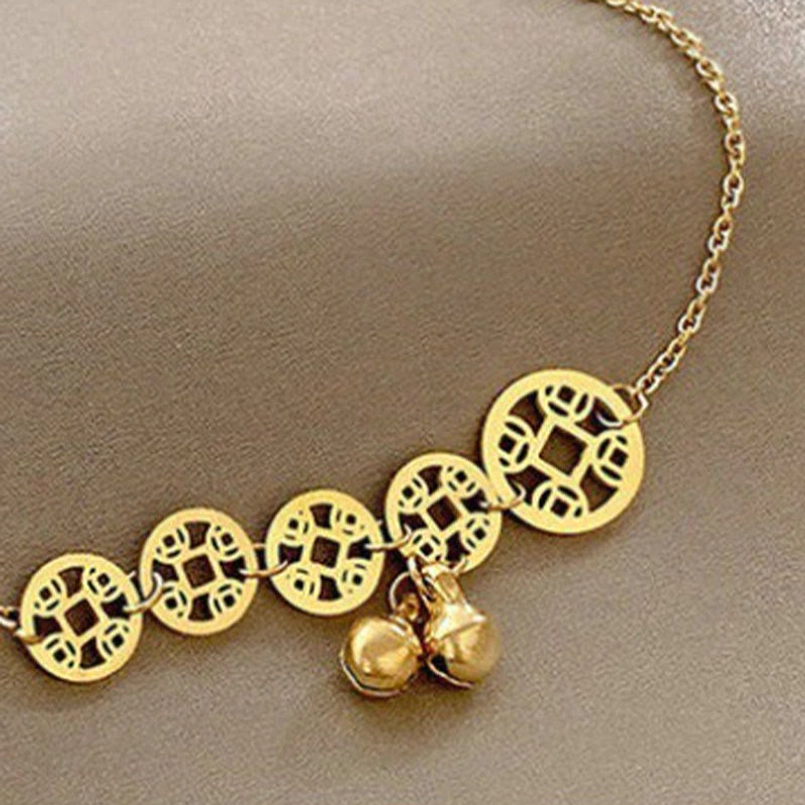 Close-up of hollow copper coins and twin gold bells on titanium steel anklet