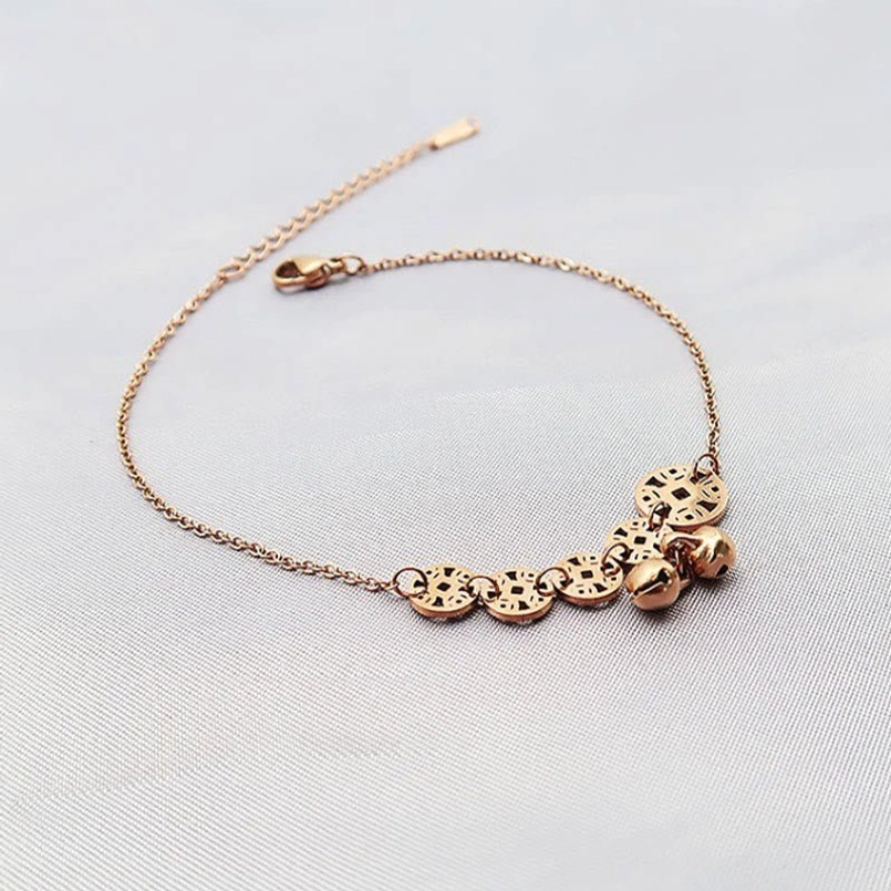 Top-down view of rose gold tone copper coins and bell pendants anklet