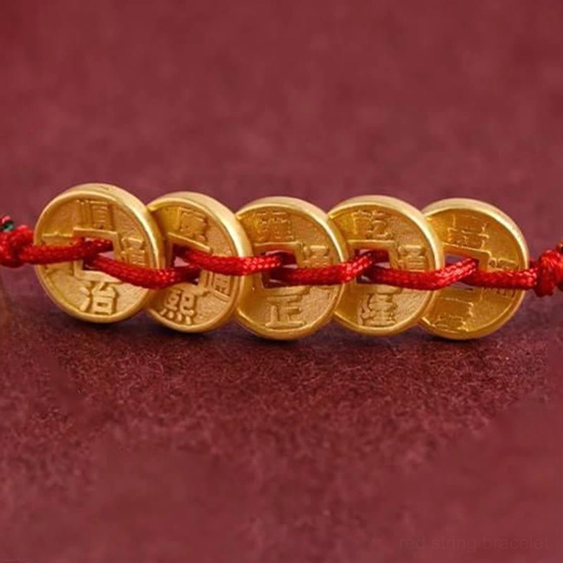 Close-up detail of five imitation ancient copper coins with Chinese characters on red string
