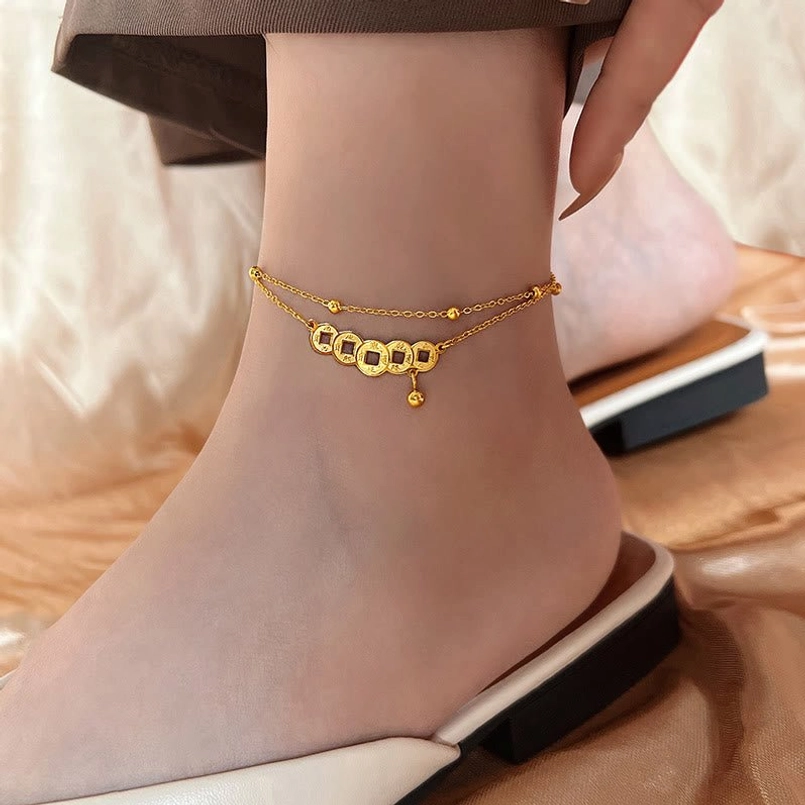 Gold titanium steel anklet with four copper coin pendants and small hanging charm worn on ankle