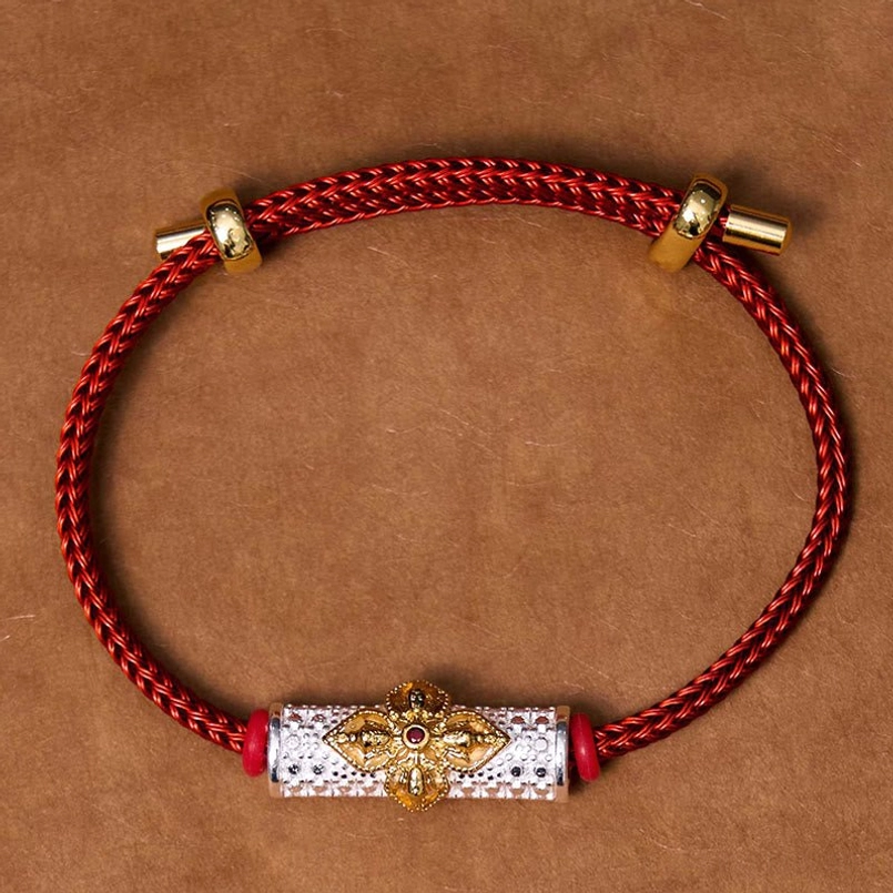 Copper luck red string bracelet detail showing flower bead with multiple enamel colors